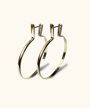 Load image into Gallery viewer, Silver hoop earrings standing upright on a white background. Large sterling silver hoops with a lip to cover your ear piercing. The hoops look substantial not flimsy, they are crafted from one piece of silver