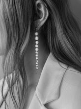 Load image into Gallery viewer, Side profile of woman showing her ear. she's wearing earrings made of graduated white pearls with black knots inbetween them. They're suspended from small domed gold studs. White freshwater pearls  •	Hand-knotted on black silk thread with an 18 ct gold plated silver stud attachment •	Length 8 cm •	Handmade in Australia