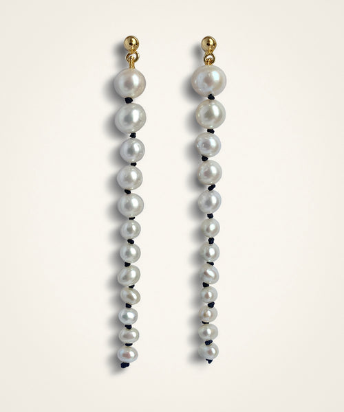set of earrings. made of graduated white pearls with black knots inbetween them. They're suspended from small domed gold studs. White freshwater pearls  •	Hand-knotted on black silk thread with an 18 ct gold plated silver stud attachment •	Length 8 cm •	Handmade in Australia