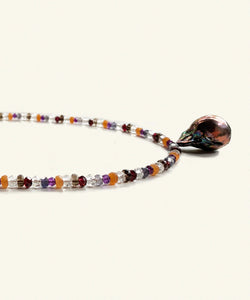 The Artemisia multi gem necklace is threaded with colour and light. Crystals such as aventurine, crystal, garnet, amethyst, iolite and smokey quartz make up a string vibrating light and protection. The finishing drop is a peacock baroque pearl.