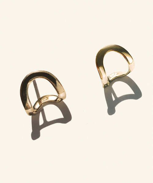 Hand made and fluid in shape, these fine golden earrings wraps around the lobe like a golden harness, exaggerating its curve.