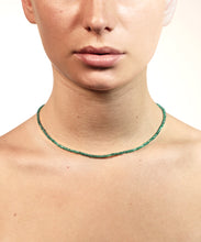 Load image into Gallery viewer, A green emerald necklace is resting on a beutiful neck. We see the bottom half of a face. The image has a white background. With gold lock and chain. The emerald is ruled by Venus, the Goddess of love and beauty, while green activates the heart Chakra. This necklace is the the ultimate confession of self love. 
